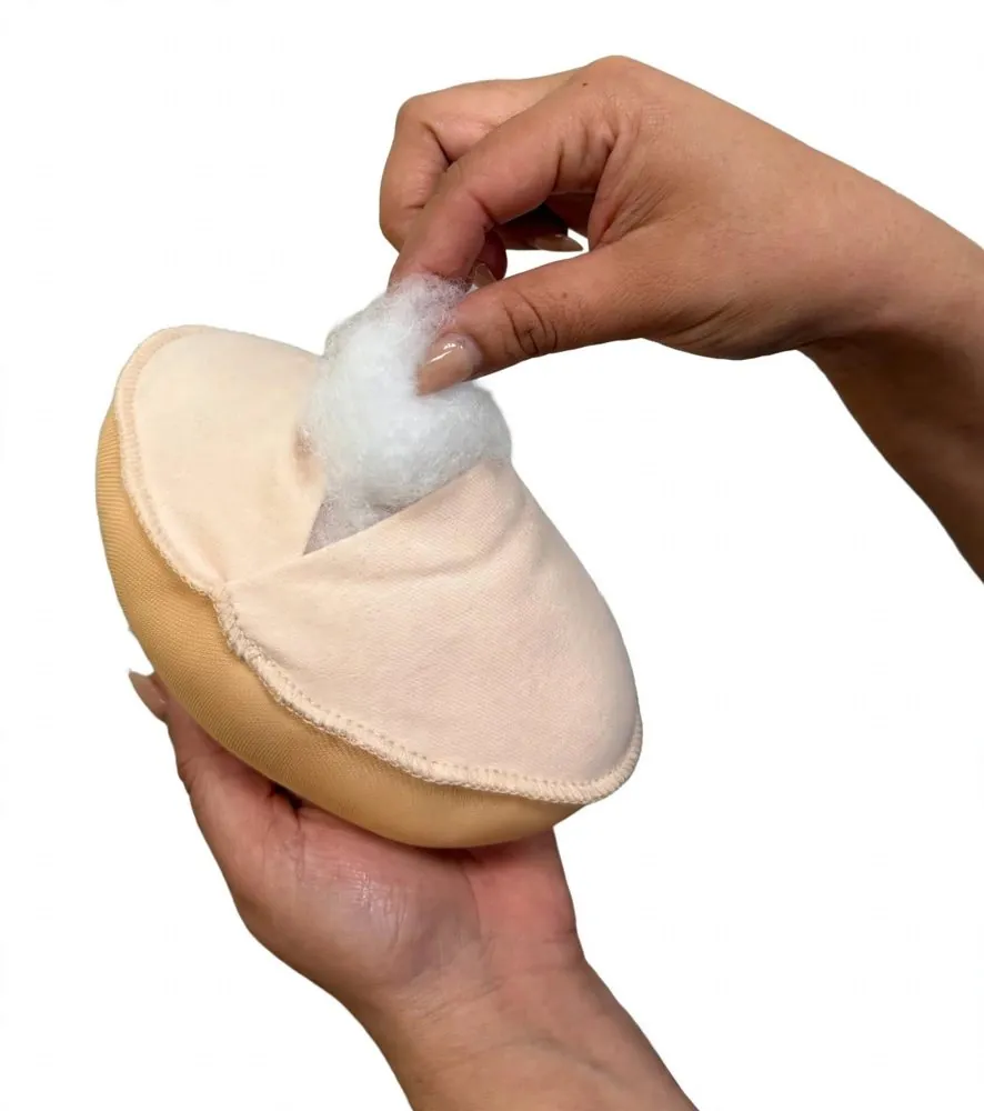Hands adding fibrefill through the opening of a fabric breast form